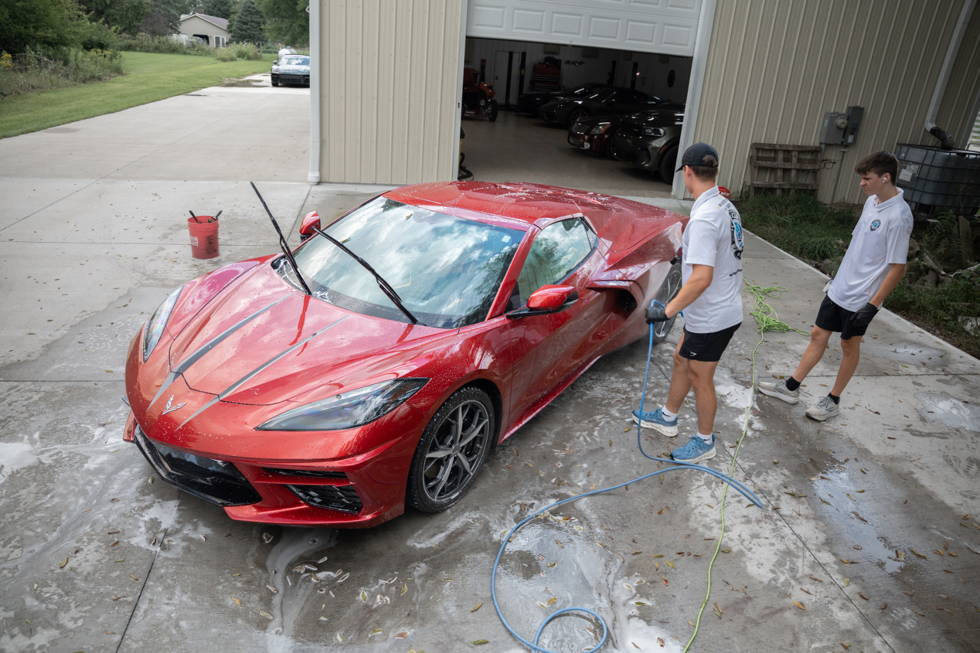 Hammond Detailing team hand-washing a red Corvette in a driveway